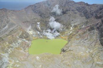 Aerial view of Whakaari/White Island, 15 December 2023 showing active steam and gas plumes and grey coloured pool (centre) now isolated from the lake. 