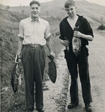 Two men holding fish stranded by the tsunami. Photo: Alexander Turnbull Library. 