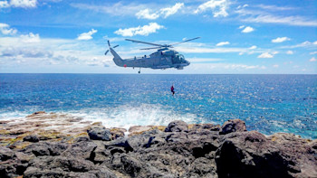 GeoNet technician, Tim 'Iceman' McDougall, dangles from a NZ Airforce's Seasprite to get access to GNSS reference mark on the rugged coast of Macauley Island. 